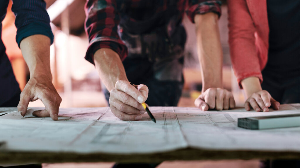 Close up of employees working on blueprints