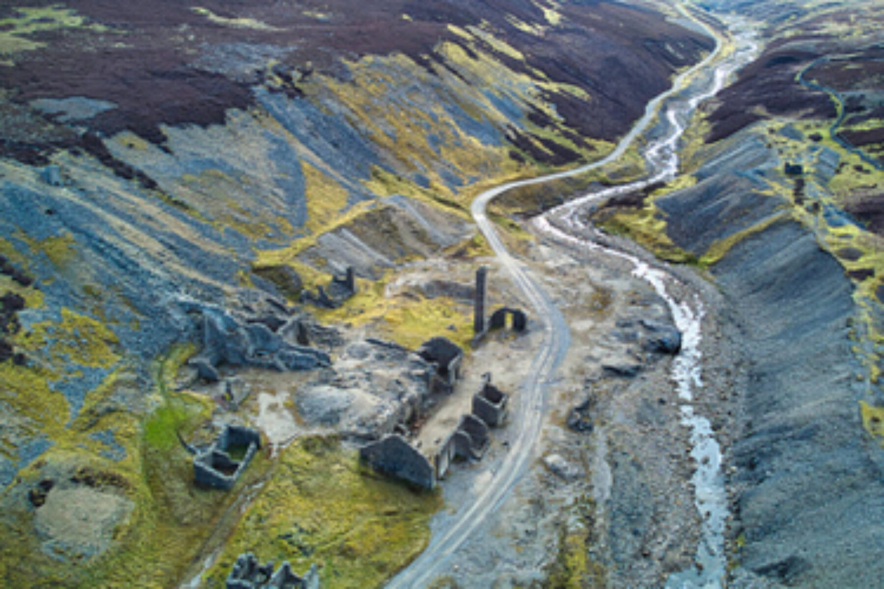 Aerial view of a mining site with a small river alongside a mining road